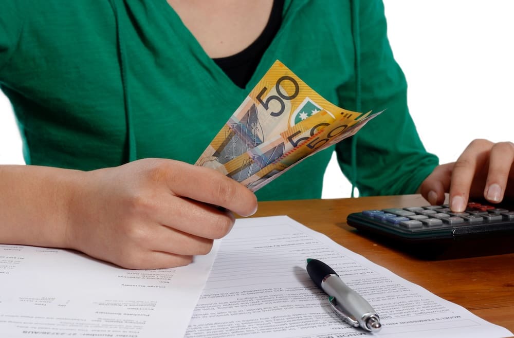 Woman in green top holding cash.